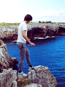 Man In White Shirt And Grey Pants Standing On Cliff photo