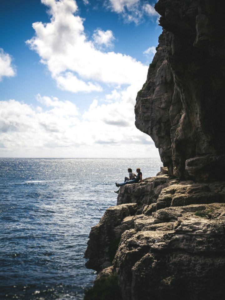 Two People Sitting By The Cliff