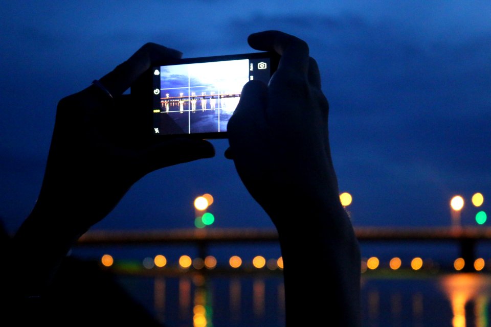 Person Taking A Photo A Of Bridge At Night