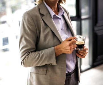 Person Wearing Suit Jacket Holding Glass Mug photo