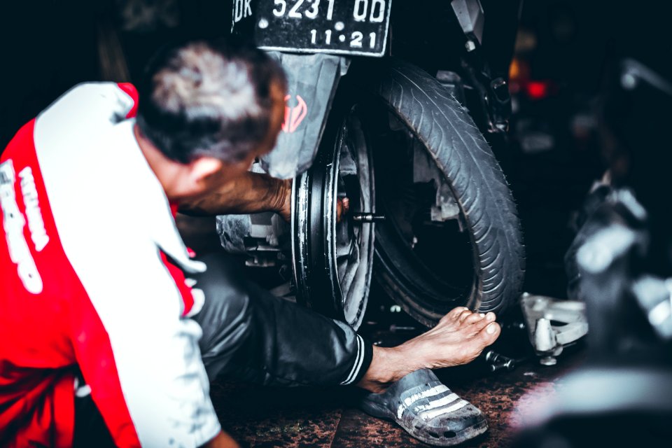 Man Changing A Rear Tire Of A Motor Scooter