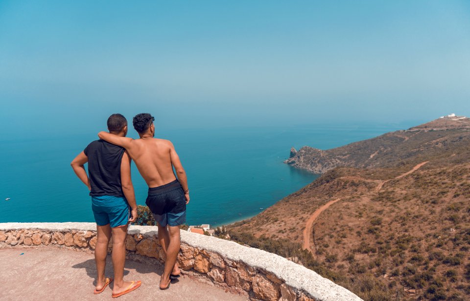 Two Man Standing On Mountain Cliff With Ocean View