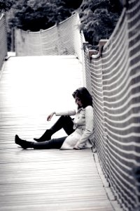 Low Light Photo Of Woman Wearing Trench Coat Sitting Against Wall