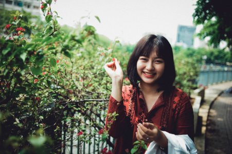 Woman Wearing Red Collared Shirt Standing Beside Plant