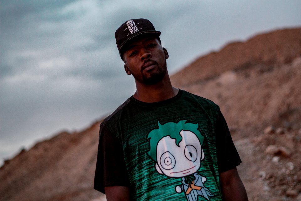 Man In Black And Green Crew-neck T-shirt Standing On Mountain Selective Focus Photography photo