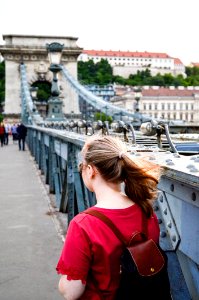 Woman Wearing Brown Leather Backpack Standing On Bridge Photo Taken photo