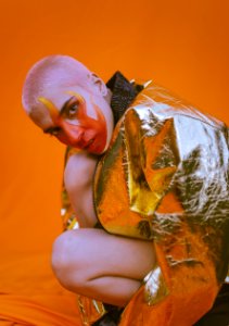 Woman Wearing Silver Zip-up Jacket Kneeling On Orange Textile photo