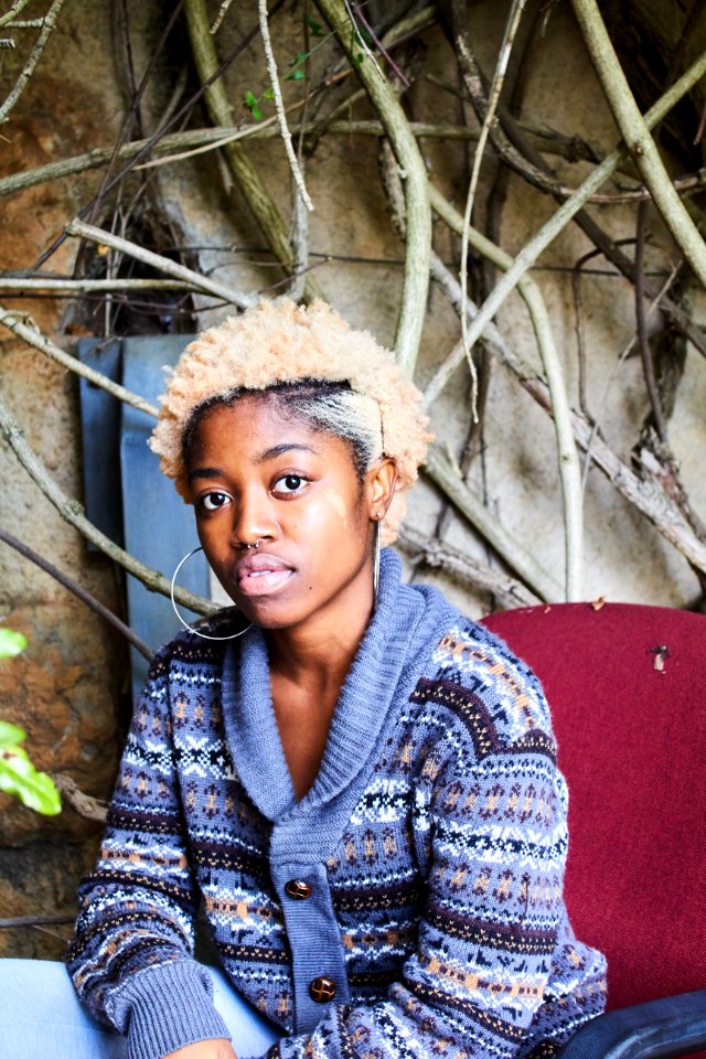 Woman Wearing Blue White And Brown Fair-isle Button-up Cardigan Sitting On Red Chair