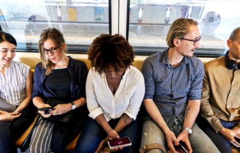 Woman Sitting Holding Smartphone Between Two Men And Two Women photo
