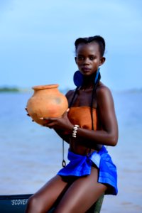 Woman Sitting On Boat Holding Brown Clay Pot photo