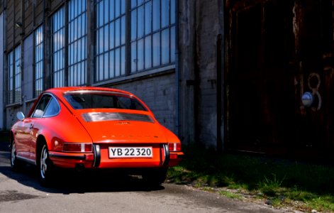 Classic Orange Coupe Near Brown Concrete Building photo