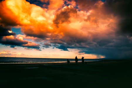 Silhouette Of People On Shore Under Cloudy Sky photo