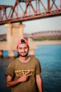 Man Wearing Gray Historic-printed T-shirt And Red Snapback Cap Taking Photo Beside Body Of Water photo