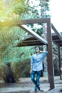 Man Wearing Blue Button-up Long-sleeved Shirt And Sunglasses Leaning On Wooden Canopy photo