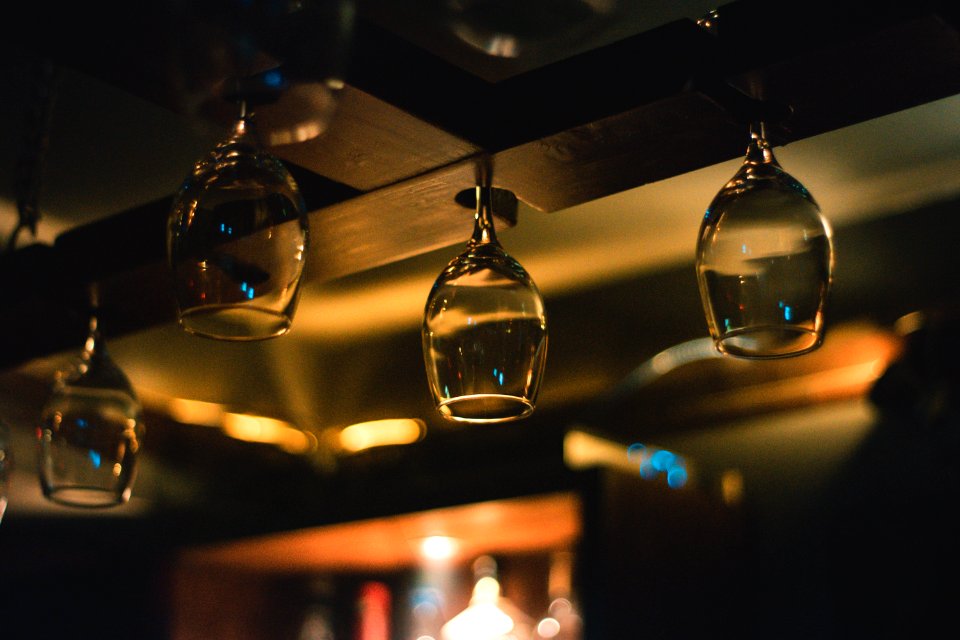 Selective Focus Photography Of Wine Glass Hanging On Black Wooden Rack