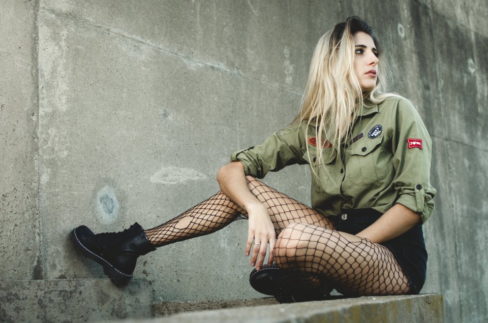 Woman Wearing Green Button-up Shirt Sitting On Grey Concrete Surface