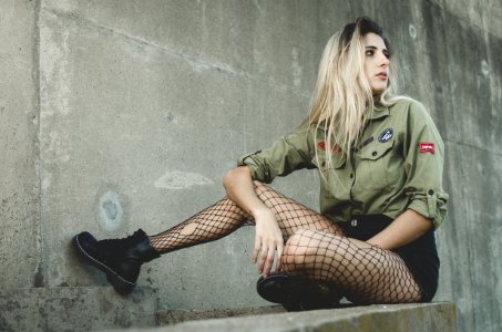 Woman Wearing Green Button-up Shirt Sitting On Grey Concrete Surface