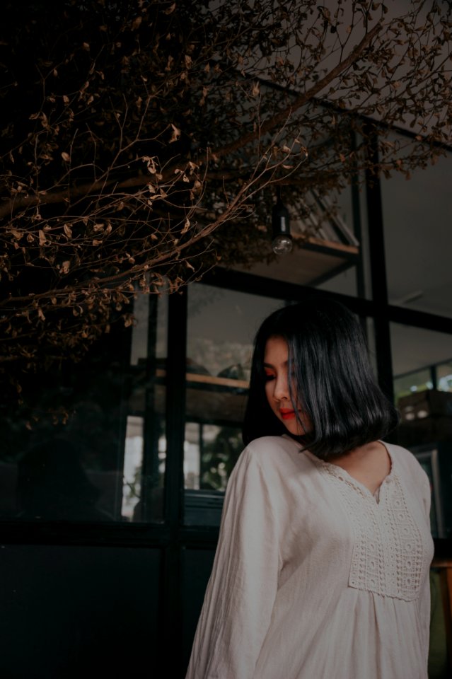 Woman Wearing White V-neck Long-sleeved Shirt Standing Beside Brown Tree photo