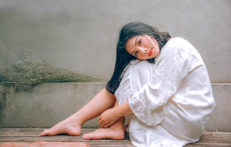 Woman Wearing White Dress Sitting On Wooden Floor photo