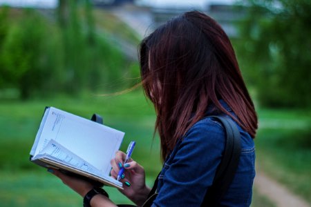 Close-Up Photography Of A Person Writing On Notebook photo