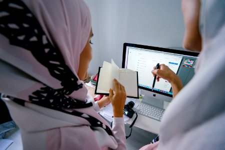 Woman In Pink Headscarf Stands In Front Of Silver Imac