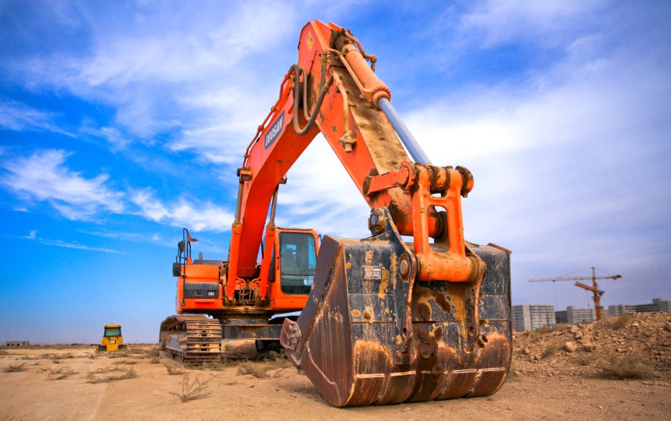 Low Angle Photography Of Orange Excavator Under White Clouds