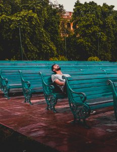 Man Sitting And Closing Eyes On Teal Bench photo