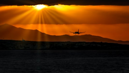 Silhouette Of Airplane Over Body Of Water