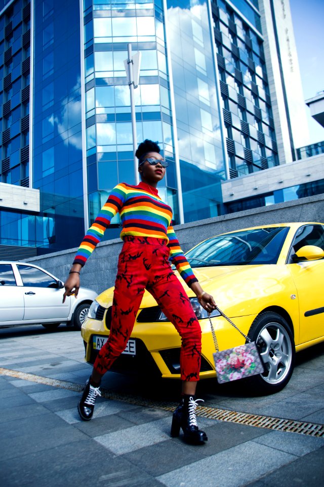 Woman Wearing Multicolored Sweater And Red Denim Jeans Near Yellow Vehicle