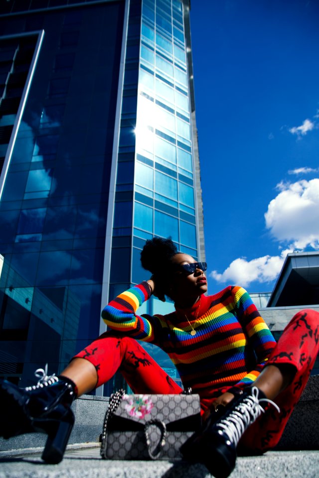 Woman Wearing Blue Red And Black Turtle-neck Long-sleeved Shirt And Red Pants Sitting On Ground At Daytime