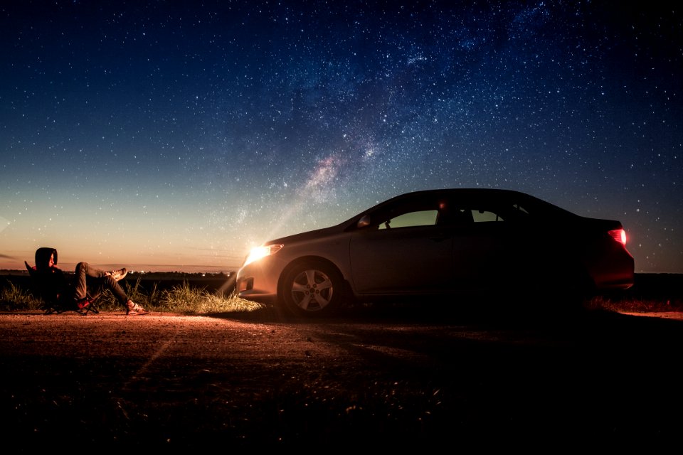 Person Laying In Front Of Silver Sedan