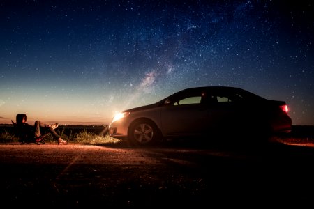Person Laying In Front Of Silver Sedan