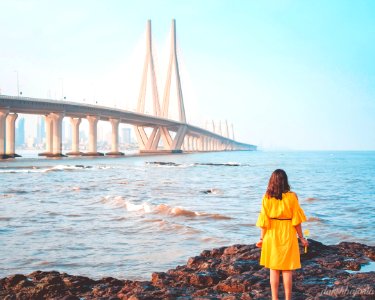 Woman Standing Near Body Of Water And Bridge photo