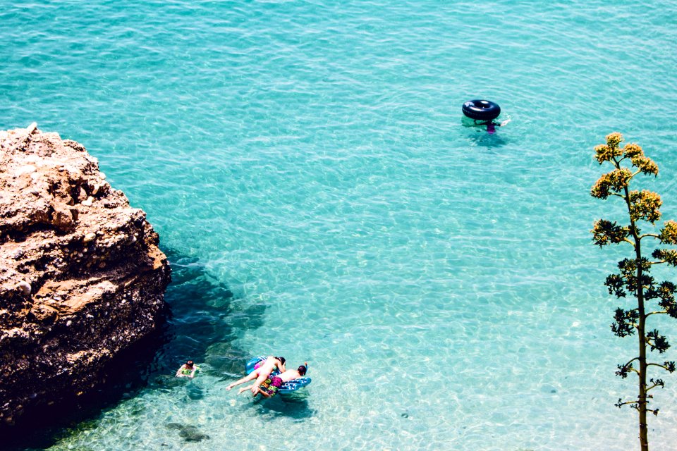 Man And Woman Swimming In The Sea Near Brown Cliff