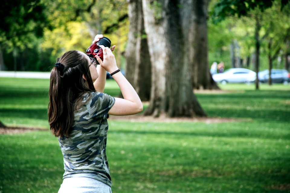 Woman Holding Maroon And Black Camera Facing Upwards
