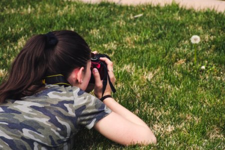 Photo Of Woman Taking Photo Of Flower On Grass