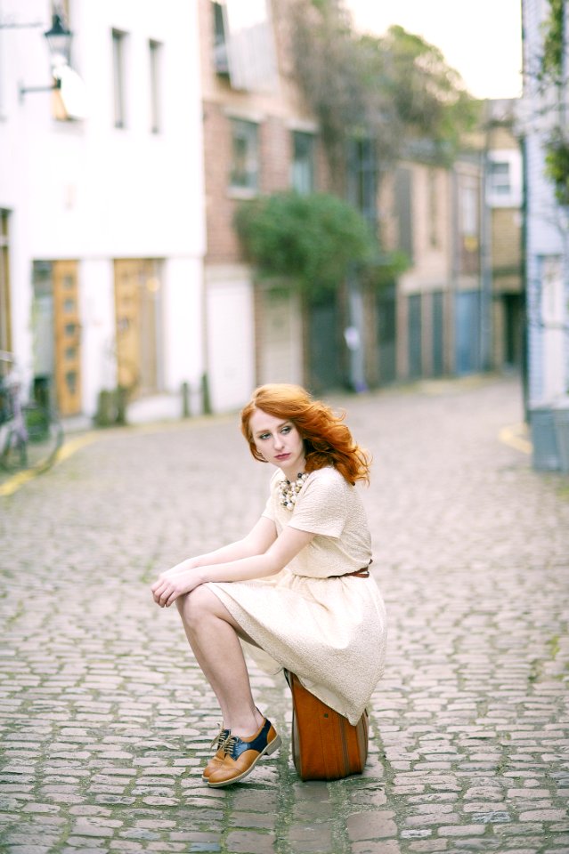 Woman Wearing White Dress Sitting On Brown Lugagge
