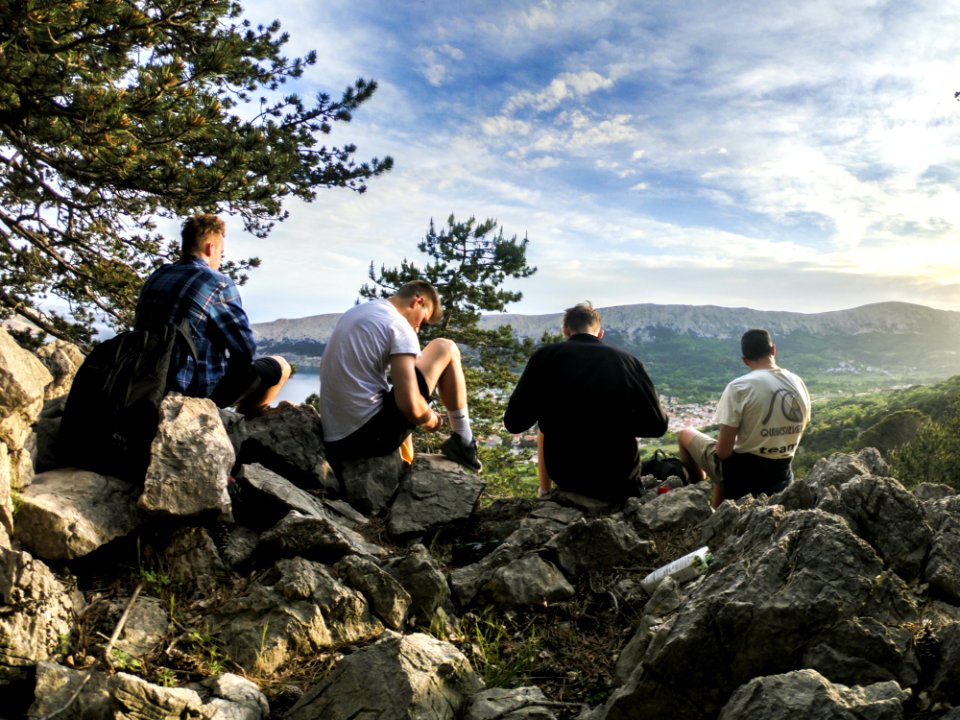 Four Men Seated On Rocks Facing Mountain