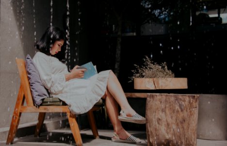 Photography Of A Sitting On Chair While Reading Book photo