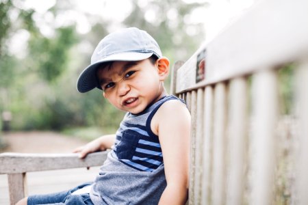 Shallow Focus Photography Of A Boy Sitting On Bench photo