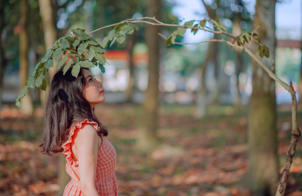 Photography Of A Woman Standing Near Leaves