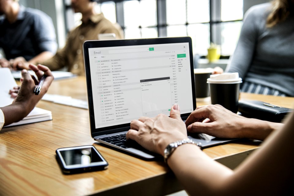 Person Using Macbook Pro On Brown Wooden Desk