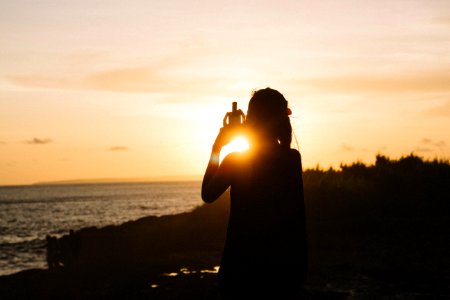 Silhouette Of Woman Standing Near Body Of Water During Sunset photo