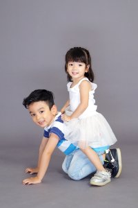 Girl In White Dress Sitting On Crawling Boys Back