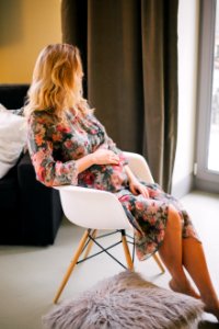 Pregnant Woman Sitting On Armchair Holding Her Tummy