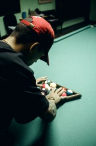 Man In Black T-shirt And Red Baseball Cap Arranging Billiard Balls On Table photo