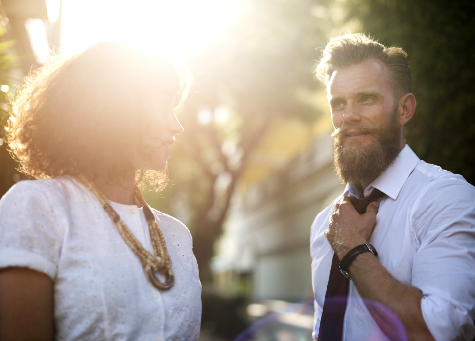 Man Holding His Necktie While Looking At Woman Wearing White Top