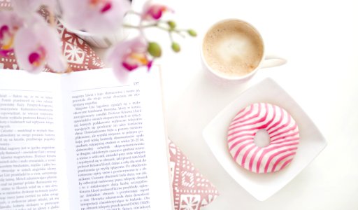 A Book Cup Of Coffee And Flavoured Donut On Square White Ceramic Bowl photo