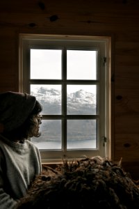 Woman Wearing Grey Sweatshirt And Grey Beanie Sitting Near Windowpane At Daytime photo