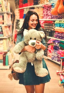 Woman Wearing Blue Top And Blue Denim Skirt Hugging A Brown Bear Plush Toy photo